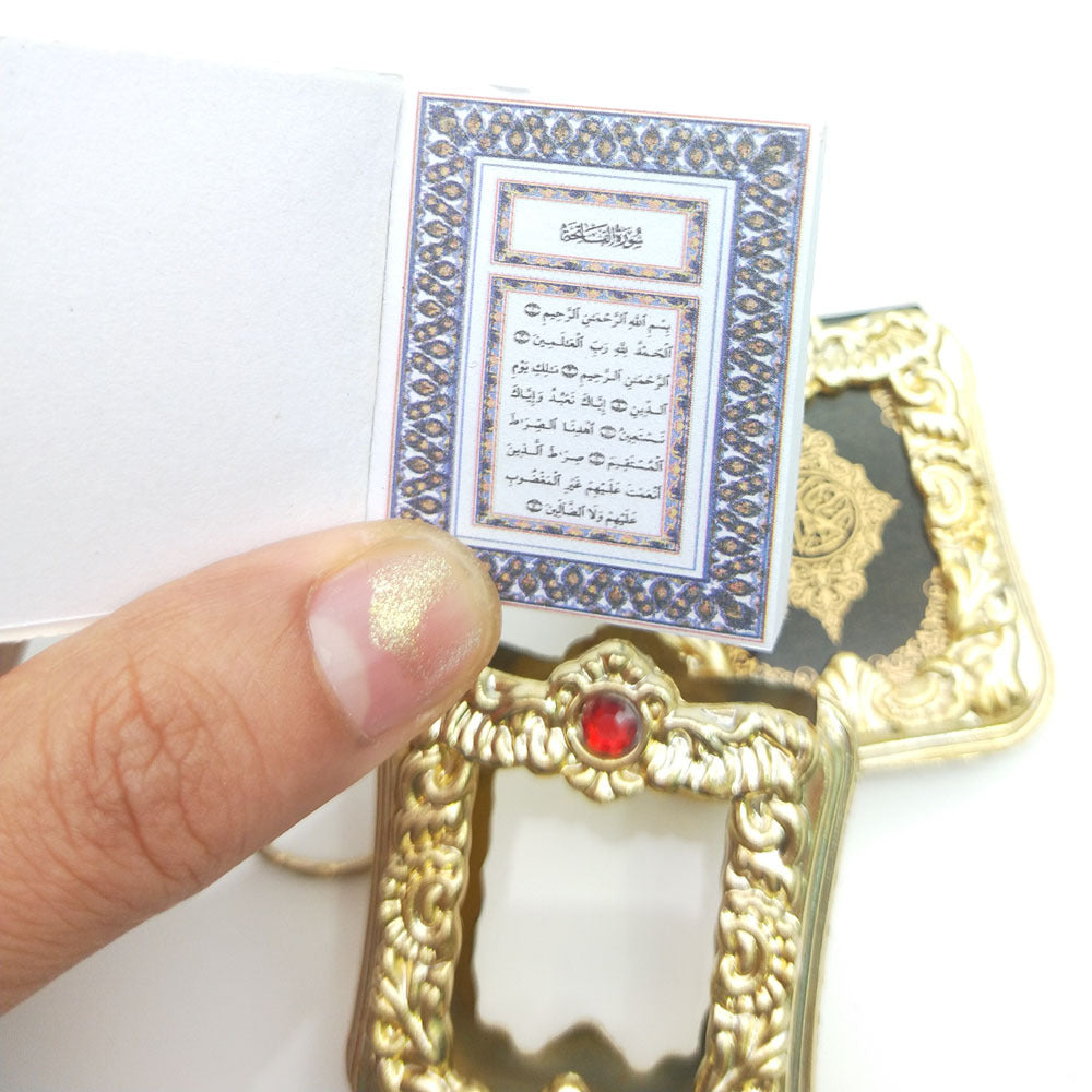 Golden Quran keychain pendant with hanging ring, featuring intricate design and compact size for carrying or display.