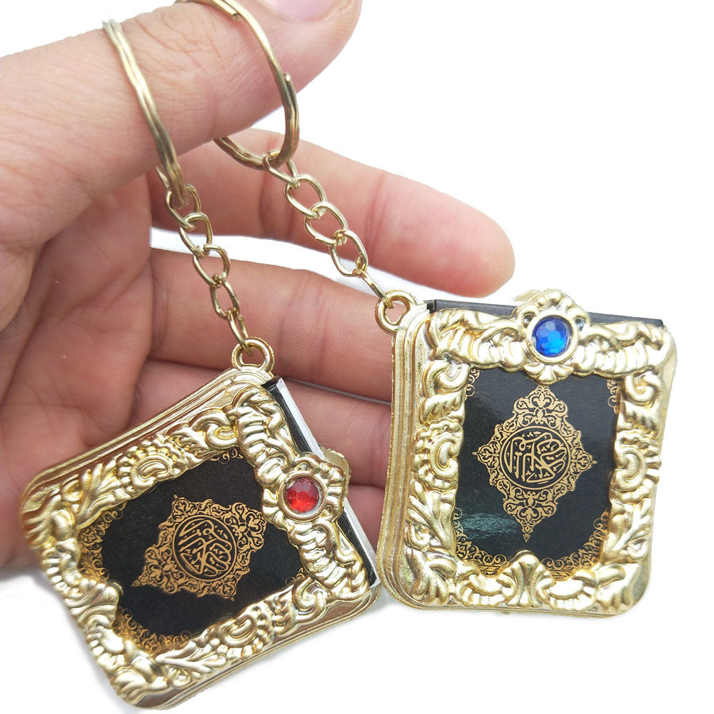 Golden Quran keychain pendant with hanging ring, featuring intricate Islamic design and religious script on the small metal tag.
